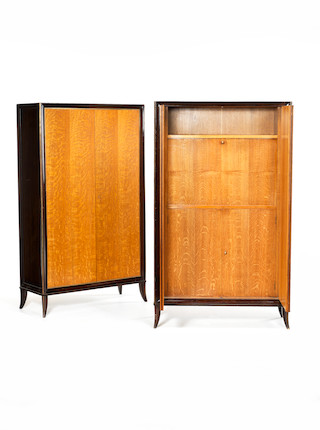 Pair of Cabinets attributed to Jean Pascaud circa 1940  oak with ebonised frame and brass trims, one with fitted interior, the upper section opening to mirrored glass panelling, the lower section with shelf, the second with three adjustable shelves, together with four keys   170 by 100 by 59 cm. 66 15/16 by 39 3/8 by 23 1/4 in. image 1
