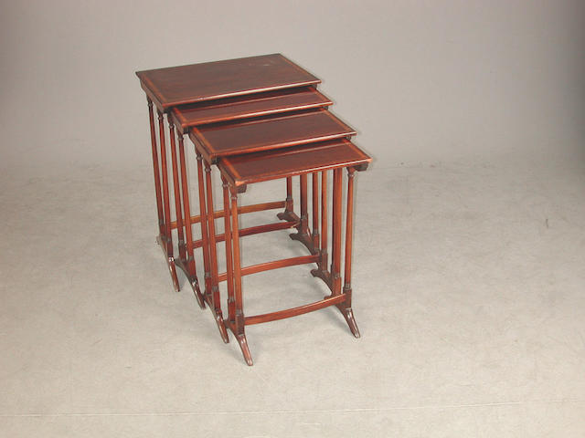 An Edwardian nest of four mahogany tables, the rectangular tops with satinwood and boxwood banding one stretcher detached, some legs...