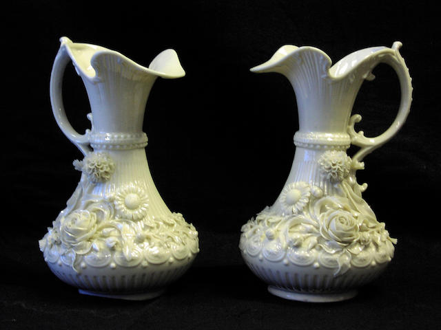 A pair of Belleck white glazed jugs,