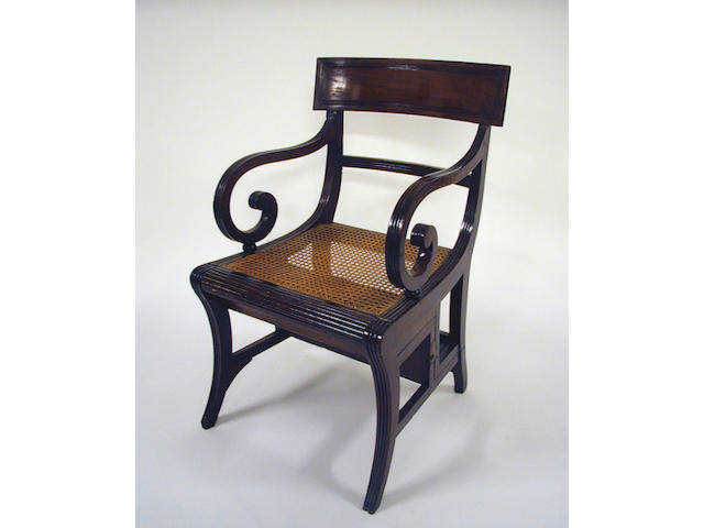 A Regency mahogany metamorphic library chair with a reeded bar back and scroll amrs above a cane panel seat on sabre legs.