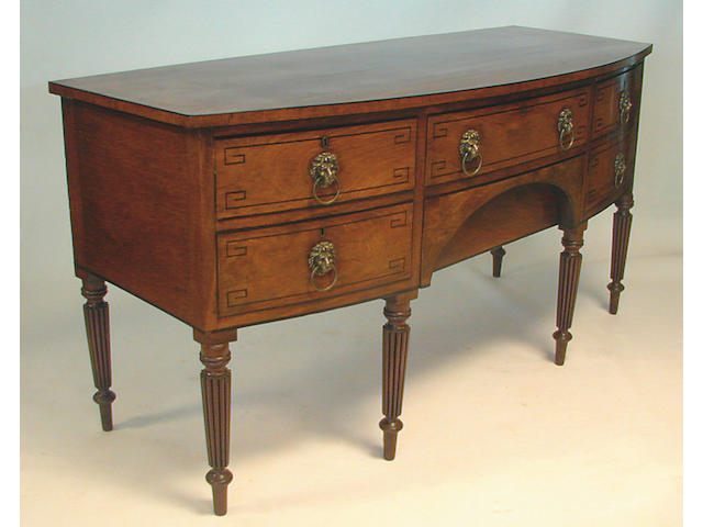 A Regency mahogany bowfront sideboard, with ebony line inlay with two central drawers and two drawers to one side anda  deep cellarette drawer to the other, with lion mask ring handles, on turned reeded tapering legs, 184cm wide.