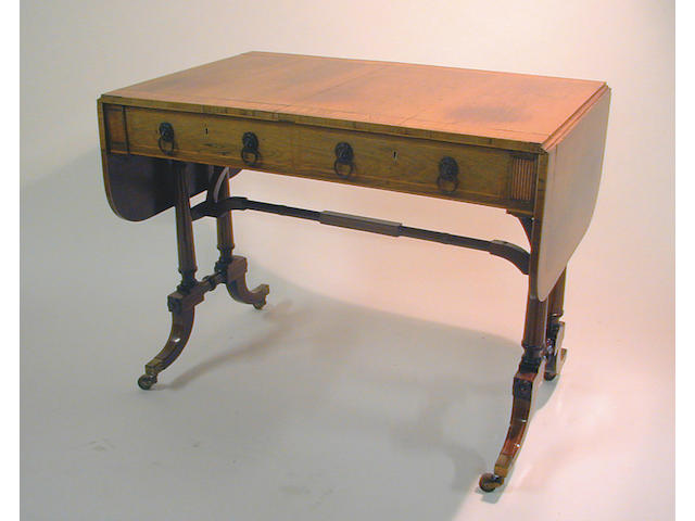 A Regency rosewood and satinwood banded sofa table, fitted with two frieze drawers opposed by dummy drawers, on dual turned end supports with outswept feet terminating in brass cappings with castors, 94cm wide.
