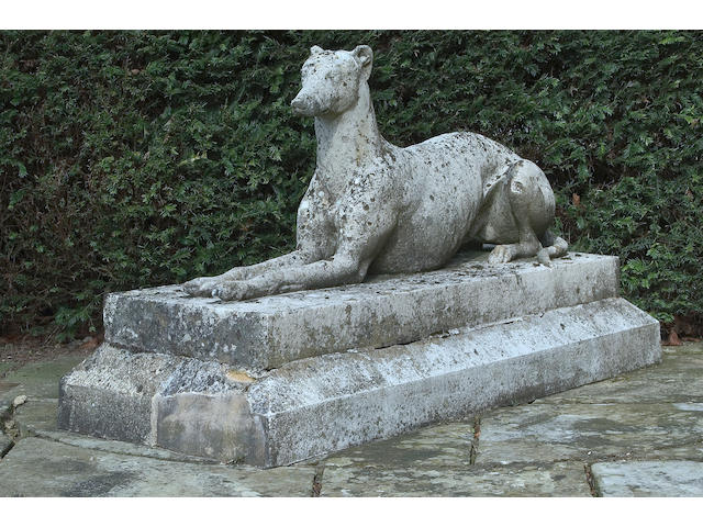A carved stone figure of a life size recumbent greyhound,
