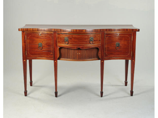A George III mahogany barber strung serpentine sideboard
