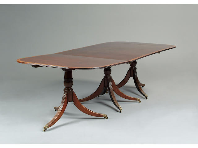 A large George III style mahogany and amboyna anded triple pedestal dining table