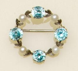 A blue zircon and cultured pearl set circular hoop brooch, spaced with foliate detail, a pearl set bar brooch applied with three flowerheads and an aquamarine set bar brooch, first brooch diamter 2.8cm. (3)