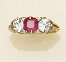 A three stone ruby and diamond ring The central round mixed-cut ruby flanked by two old-brilliant cut diamonds, with diamond points between, claw set in pierced scrollwork mount, ring size J.