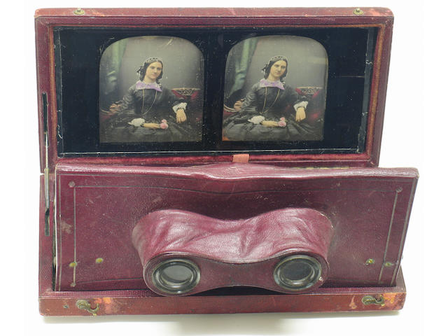Antoine Claudet Stereo Daguerreotype Stereoscopic daguerreotype of a seated lady holding a rose in Claudet's gilt crested red leather folding stereo viewing case; mid to late 1850's with label on reverse of backing paper with Claudet's information and the address "107 Regent Street" . A finely tinted and gilded example of a charming subject, Claudet is most known today for his fine portraits.Note; Claudet patented his viewing case March 23 1853. The views can be removed by pulling on a ribbon i