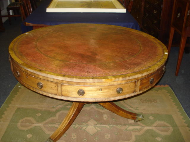 A George III faded mahogany drum top library table, the inset top over four real and four alternate dummy drawers, on a tapering column and three sabre legs, 111cm diameter.