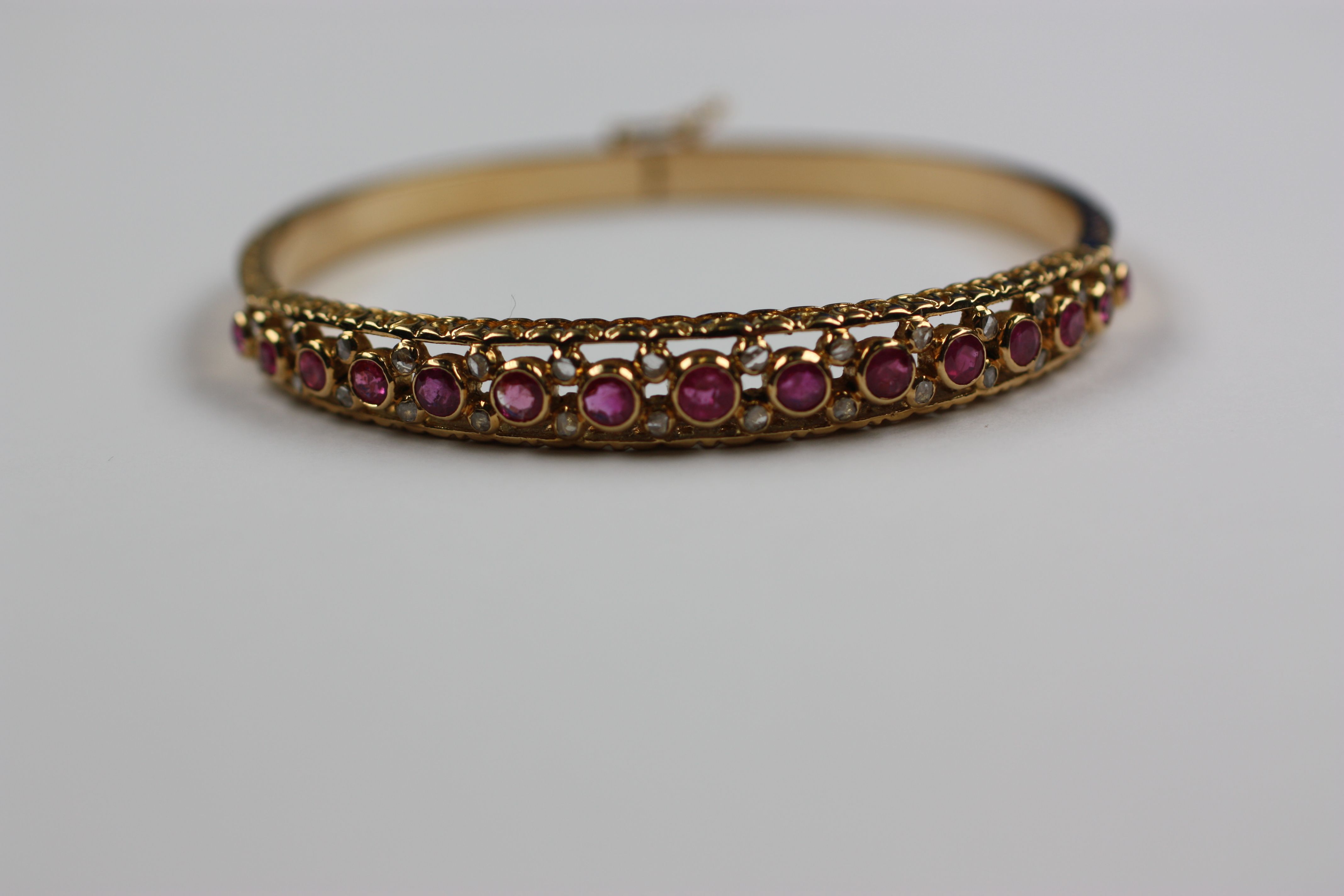 A modern 18ct gold ruby and diamond set hinged bangle