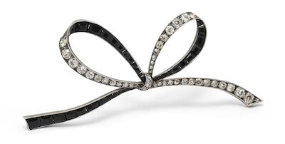 An onyx and diamond brooch of silver and 14k gold in the shape of a bow. L. 9 cm. Early 20th century.