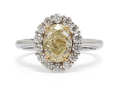 A diamond ring set with an oval-cut yellow diamond encircled by diamonds, mounted in 18k white gold. Size 53.5.