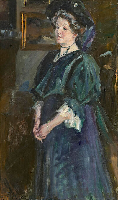 P. S. Krøyer: Mrs. Henny Brodersen (1868-1960). Signed and dated S. K. Skagen 1907. Oil on canvas. 80 x 48 cm. "Fru Henny Brodersen i mørk blaa og grøn Dragt med mørk Hat. Staaende Figur. Baggrunden et Maleri i forgyldt Ramme". Mrs. Henny Brodersen (1868-1960) standing in a blue and green dress wear