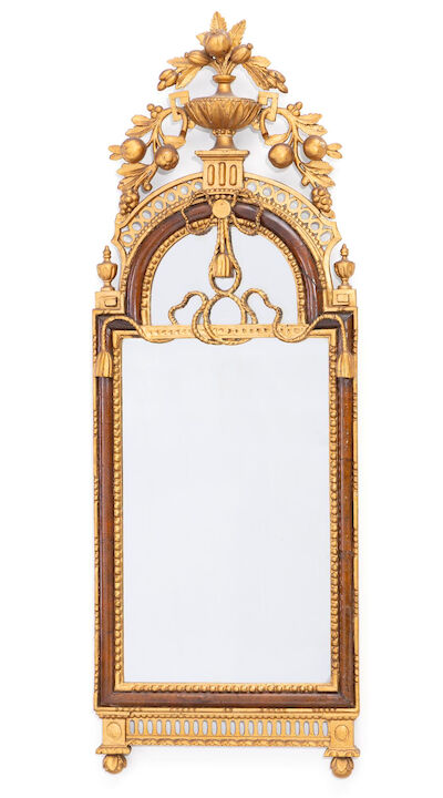 An Altona Louis XVI mirror of walnut and later gilded wood, portal-shaped frame carved with urn, fruits and foliage. Late 18th century. H. 120 cm. W. 42 cm.