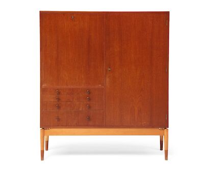 Finn Juhl: A teak cabinet with maple frame. Front with seven drawers with round handles, flip-down leaf with table function and one door. A teak cabinet with maple frame, teak "shoes". Front with seven drawers with round handles, flip-down writing leaf and one door. Maple interior with shelves and t