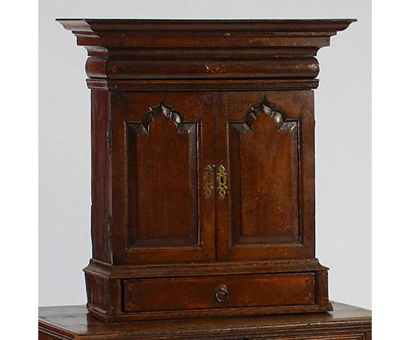A late 17th century oak table cabinet, the pair of panelled doors enclosing an arrangement of eight drawers and four pigeon holes en...