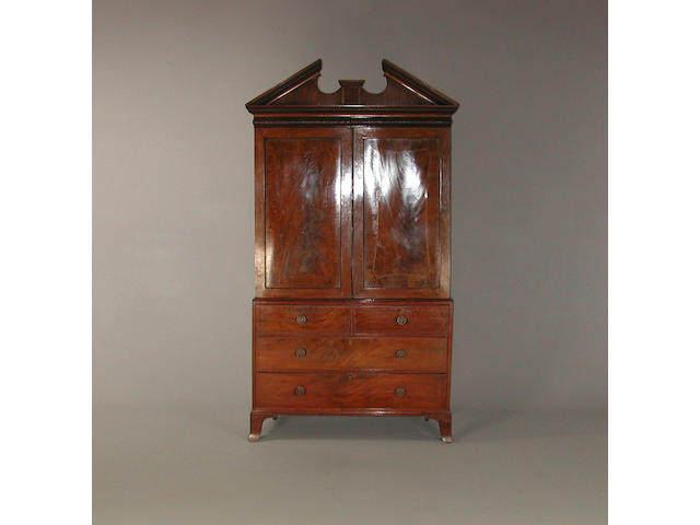 A Regency mahogany linnen press,  the broken pediment above cupboard doors and two short and two long drawers on splayed bracket feet 124 cm wide by 55 cm deep x 234 cm high