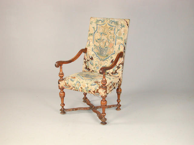 A walnut open armchair, with 18th century floral tapestry panals to the back and seat, on turned legs united by an x strtcher