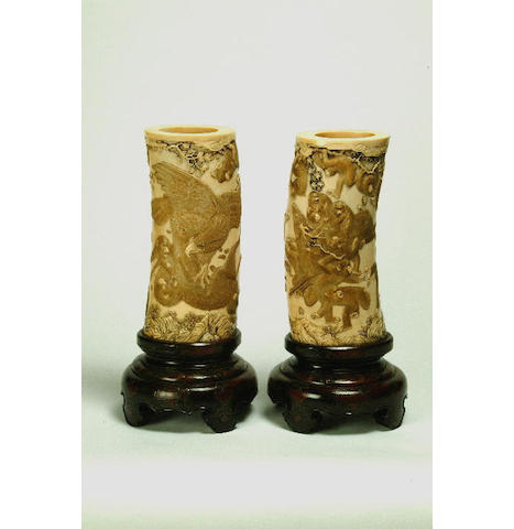 A pair of Japanese ivory tusks elaborate hardwood stands, tusks 24 cm high, stands 11 cm high. (2)