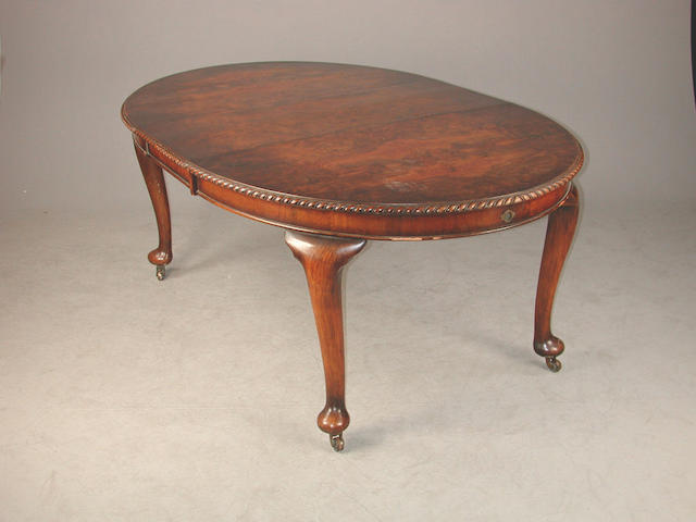 A figured walnut extending dining table, the gadrooned edge over cabriole legs with pad feet and castors early 20th century, two lea...