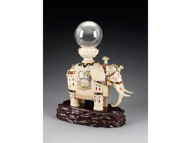 A very fine ivory okimono of a standing elephant, with glass ball and wood stand [3]