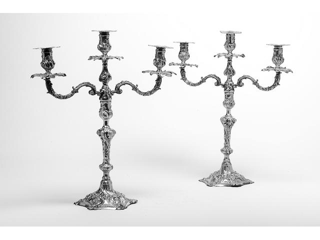 A pair of George III cast candlesticks, by William Cafe, London 1768, fully marked to bases, the capitals of the sticks with maker's mark and lion passant, each nozzle marked with a lion passant and numbered, and a pair of associated branches, variously marked with a lion passant and maker's mark, the drip pans also marked with a lion passant,