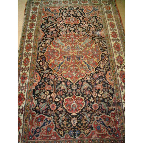 A Bijar rug, the dark indigo field with flowering vines, a madder floral medallion within an ivory cartouche border (slight fraying to both ends), 1.46 x 2.40m