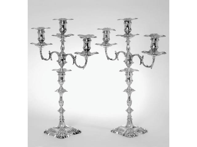 A pair of George II cast candlesticks with Victorian three-light candelabra branches, the sticks by William Gould, London 1758, the branches by John Aldwinckle and Thomas Slater, London 1892,