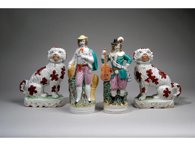 A pair of Staffordshire pottery spaniels, second half 19th century, each modelled seated with iron red details on a rectangular scroll moulded plinth, one smoking a pipe, 27cm. (2)