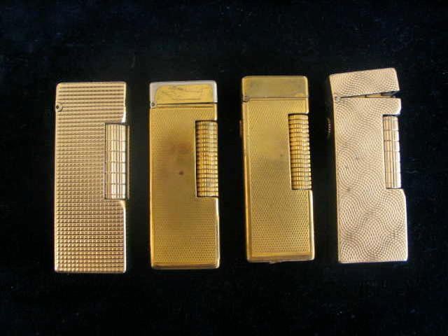 Two gold "Dunhill" Lighters together with two yellow metal examples, (4)