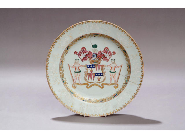 A Qianlong armorial dish Centred with a full achievement of arms in puce, blue, green and gilt, the cavetto decorated with fruiting vine and the rim slip decorated with stylized flowers and foliage, 38cm diameter.