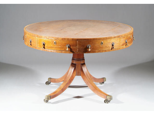 A George III mahogany drum table With leather lined top and fitted with four frieze drawers flanked by dummies, on turned column and quadruple splayed legs and brass capped castors, 114cm diameter.
