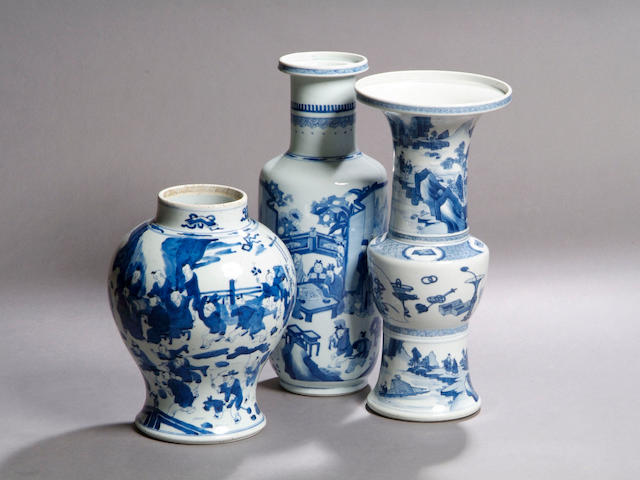 A Kangxi blue and white rouleau vase Decorated with a continuous scene of figures socialising, 46.5cm high.