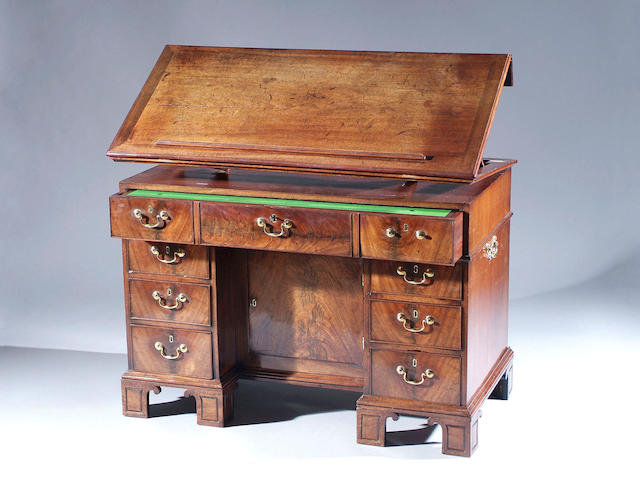 An early George III mahogany architects kneehole desk With adjustable top, fitted with frieze drawer with baize lined slide and six further drawers flanking a recessed cupboard, on panelled bracket feet and having carrying handles, 120cm wide.