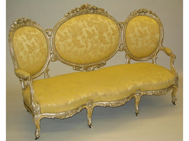 A mid-19th Century Louis XV style cream and silvered, carved beech frame upholstered settee,