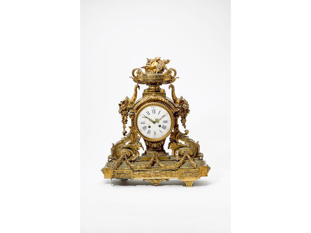 A large and impressive late 19th century / early 20th century French gilt brass wall clock Surmounted by twin handled urn over fruiting cornucopia and a shaped base, the 6.75 inch enamel Roman and arabic dial with fancy hands (cracked and chipped), the large circular movement with platform escapement striking on a bell 68cm (2ft 3in) high.