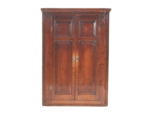 A George III oak wall mounted corner cupboard