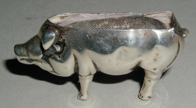 A silver pincushion in the shape of a standing pig,
