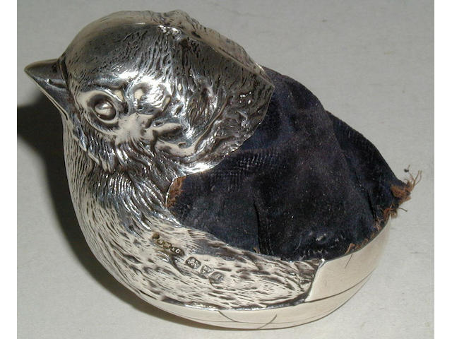 A large silver pincushion in the form of a chick emerging from a shell,