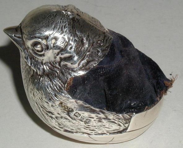 A large silver pincushion in the form of a chick emerging from a shell,