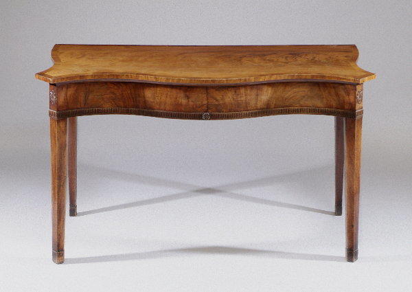 A George III mahogany serpentine serving table With crossbanded top above a deep frieze with fluted band, on square tapering legs and spade feet, 145cm wide.