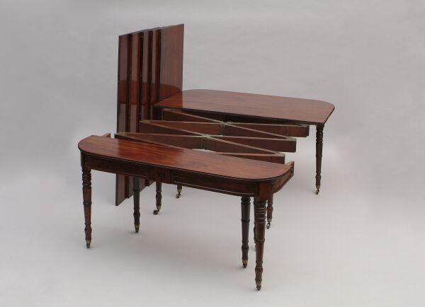 A George IV mahogany concertina action extending dining table Closing with a hinged fold-over leaf, the top with rounded corners above a panelled frieze, supported on ten ring turned legs with brass caps and castors, including five later leaves, 351 x 135cm extended (53 x 135cm closed).