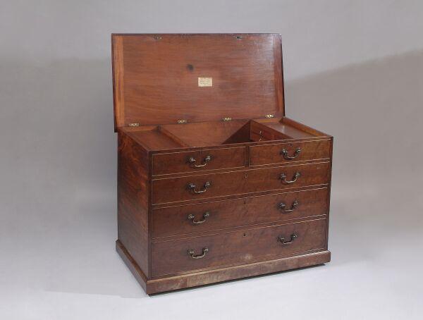 An unusual George III mahogany chest In the form of a chest with two short and three long drawers, the top hinged to reveal a fitted compartment, the front with three dummy drawers and two long drawers, on plinth base, 125cm wide.