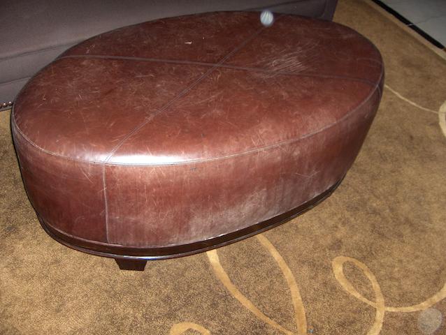 A large oval brown leather upholstered stool