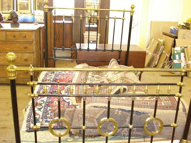 A late 19th century black painted iron and brass mounted double bed,