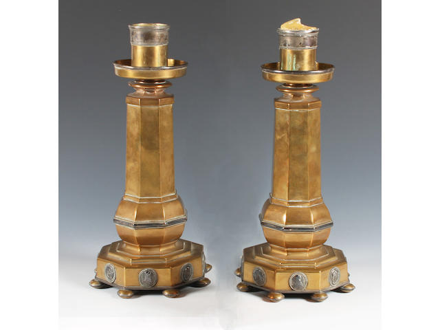A pair of Arts and Crafts brass and electroplate mounted candlesticks in the style of Henry Wilson