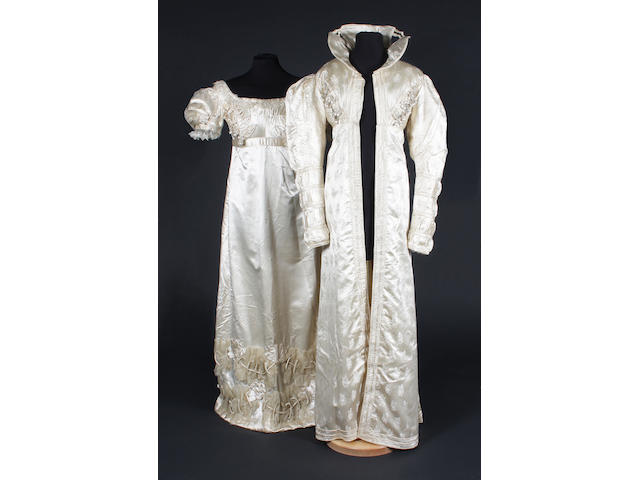 An early 19th century redingote of figured cream silk and a cream silk dress