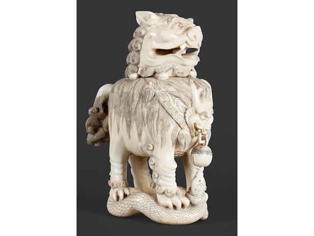 A large carved ivory figure of a lion dog standing on a snake, 23cm high,