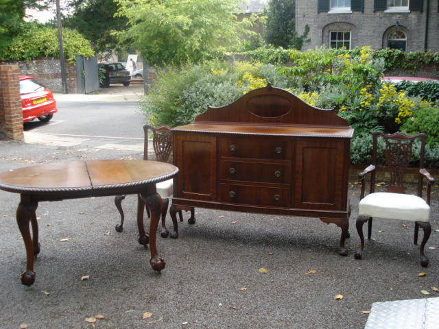 A set of eight 'Chippendale Revival' carved mahogany dining chairs, with pierced ribband vase splat backs, stuff over seats, on cabriole legs, ball and claw feet to include a pair of elbow chairs, a similar style and period extending dining table, the oval top with two extra leaves and gadroon edge, on carved cabriole legs, ball and claw feet, winding handle and a sideboard fitted with drawers and cupboards. (10)