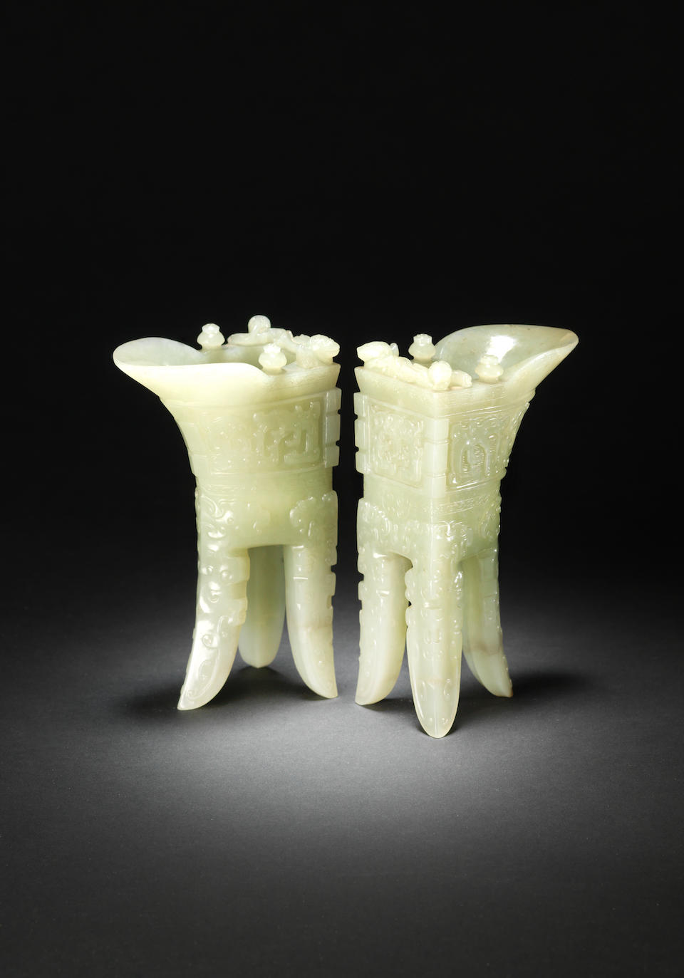An important and rare pair of archaistic pale green jade wine vessels, jue Incised Qianlong four-character marks and of the period